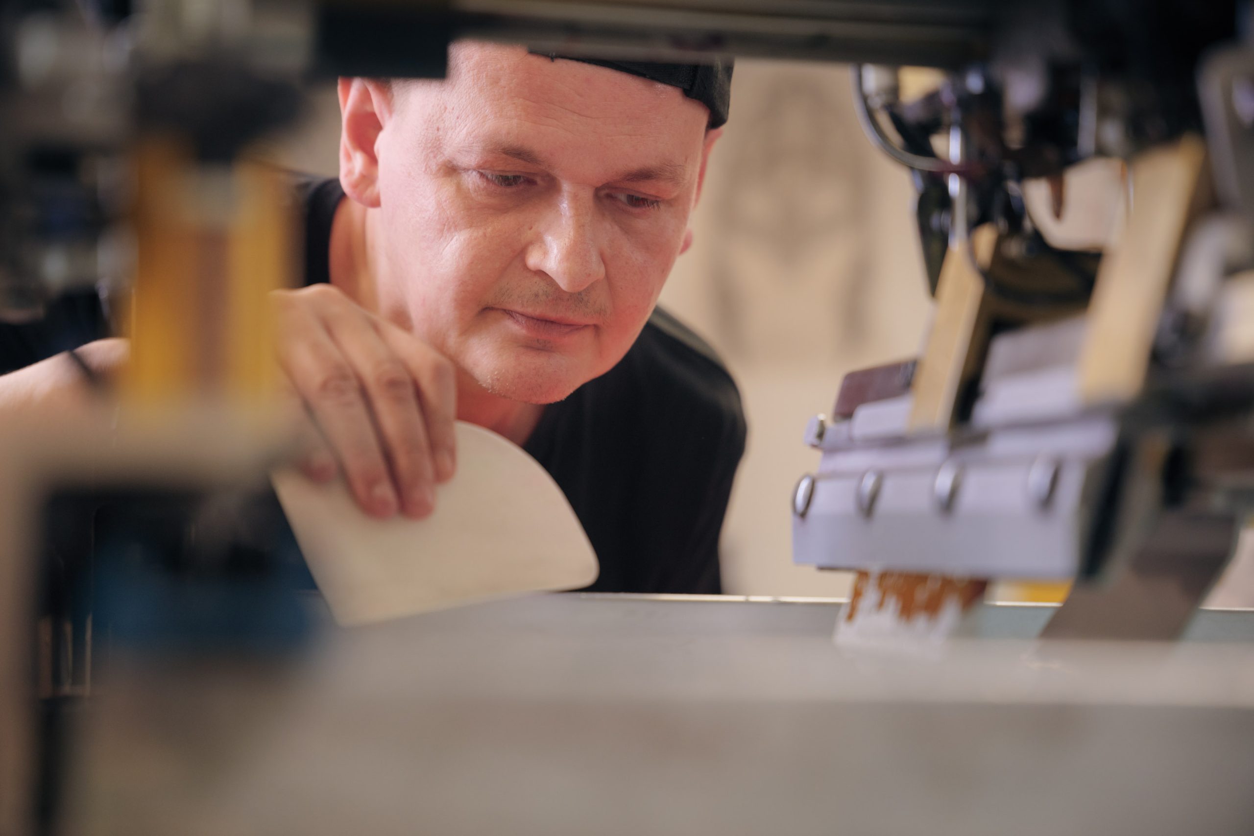 Nahaufnahme: Konzentration im Gesicht des Mitarbeiters, der eine Textildruckmaschine bedient