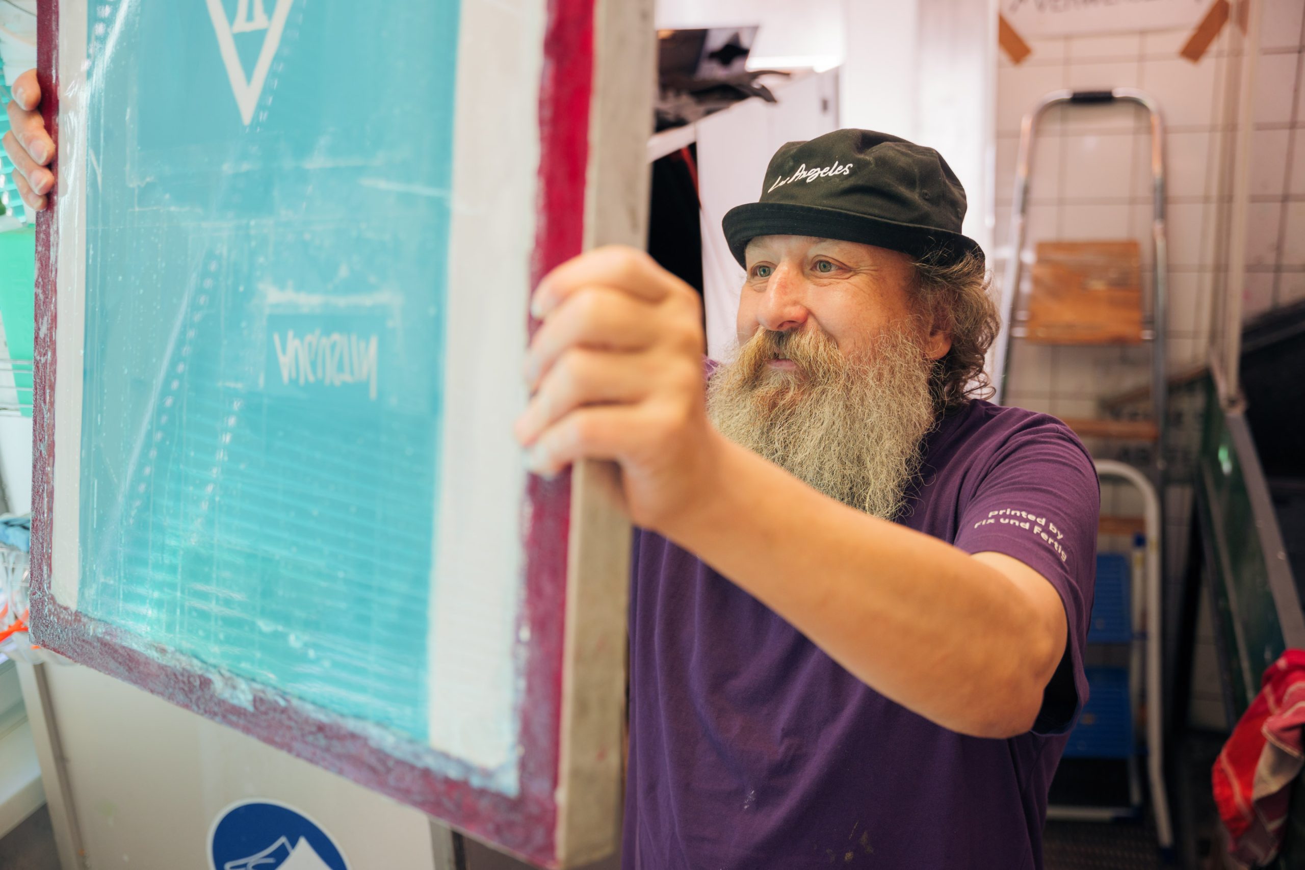 Beim Textildruck: Ein Mitarbeiter begutachtet einen Siebdruckrahmen